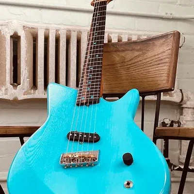 A blue solid body electric guitar with a maple neck, leaning against a chair.