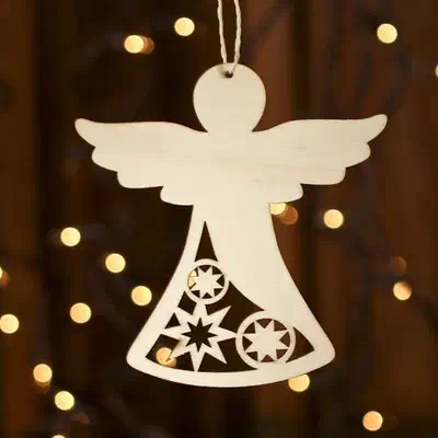 Pale wooden angel ornament with openwork skirt hanging in front of warm tree lights