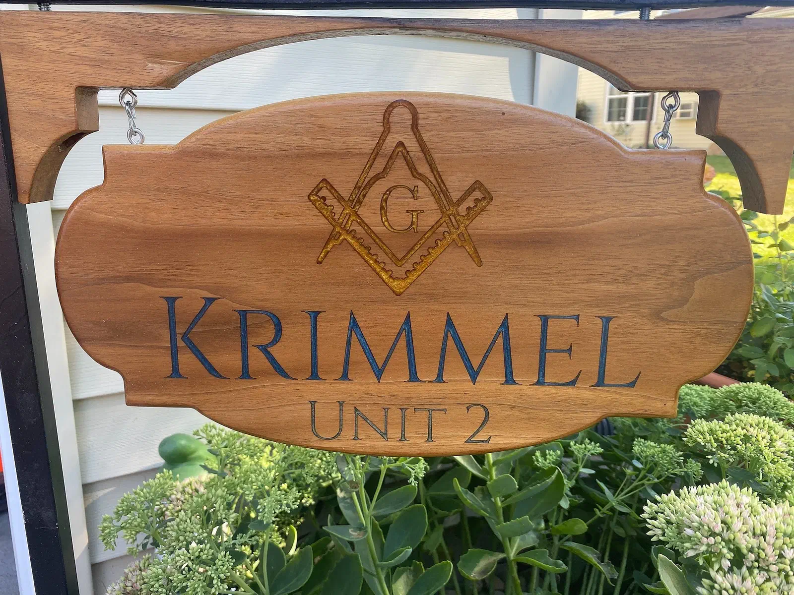 Finished hanging wooden Krimmel Unit 2 sign with a carved Masonic emblem and blue-filled lettering