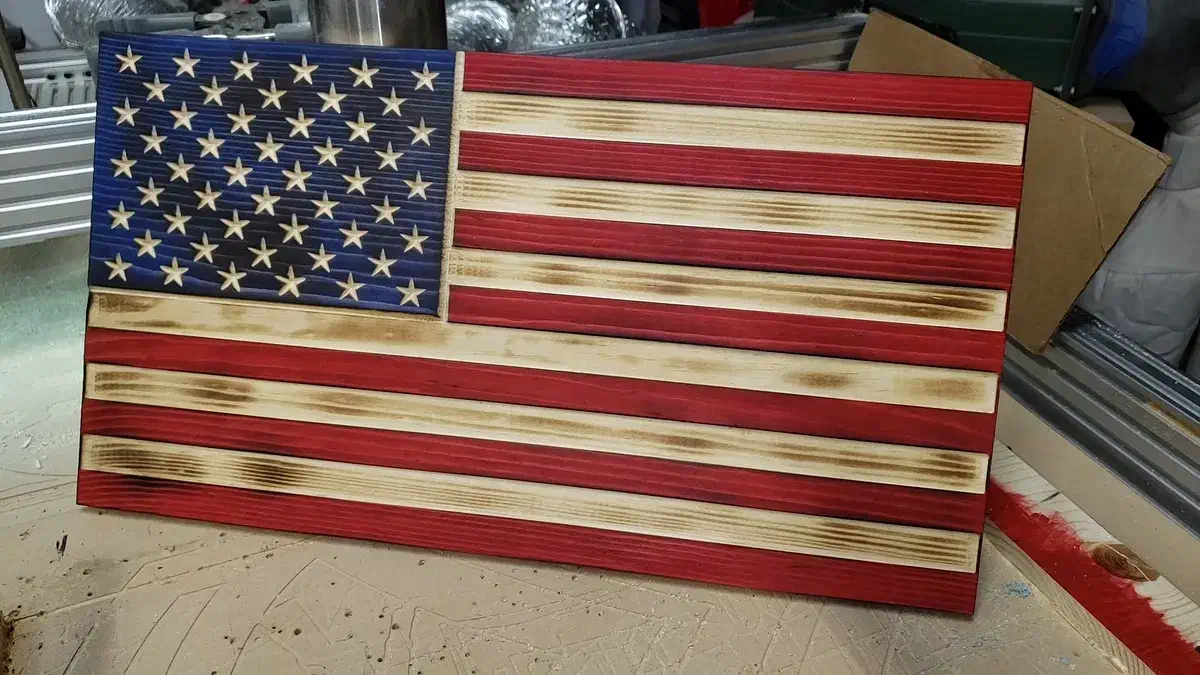 Finished red, white, and blue wooden American flag with carved stars and scorched natural wood stripes