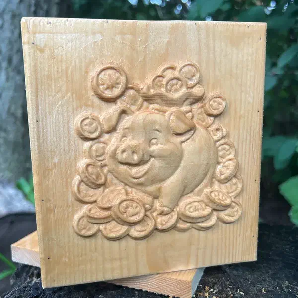 A wooden bank front with a smiling pig and coins carved in relief, photographed outdoors