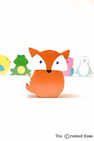 A painted orange fox coin bank with other painted animal banks behind it