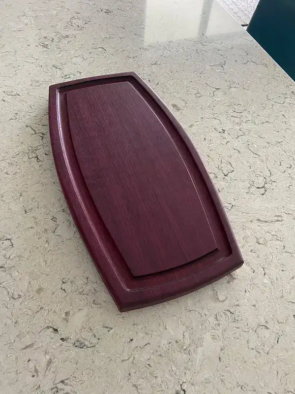 A finished purple wooden board with a juice groove around its edge
