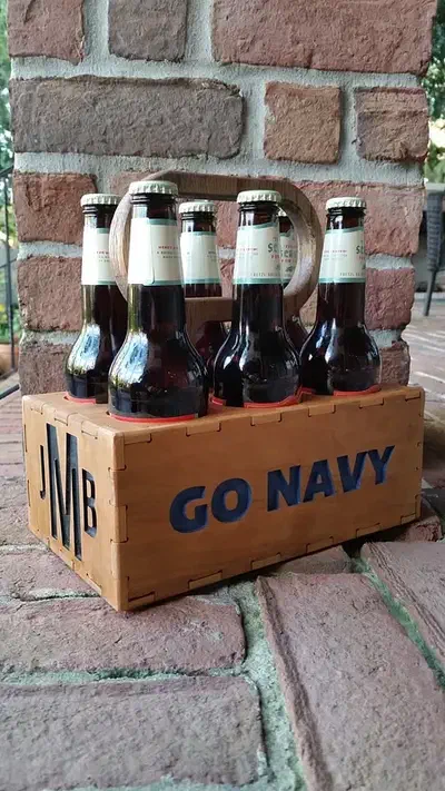Wooden six-bottle carrier filled with bottles beside a brick wall