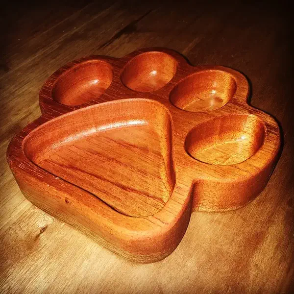 A polished wooden paw-shaped bowl with four round toe pockets and a larger central pocket