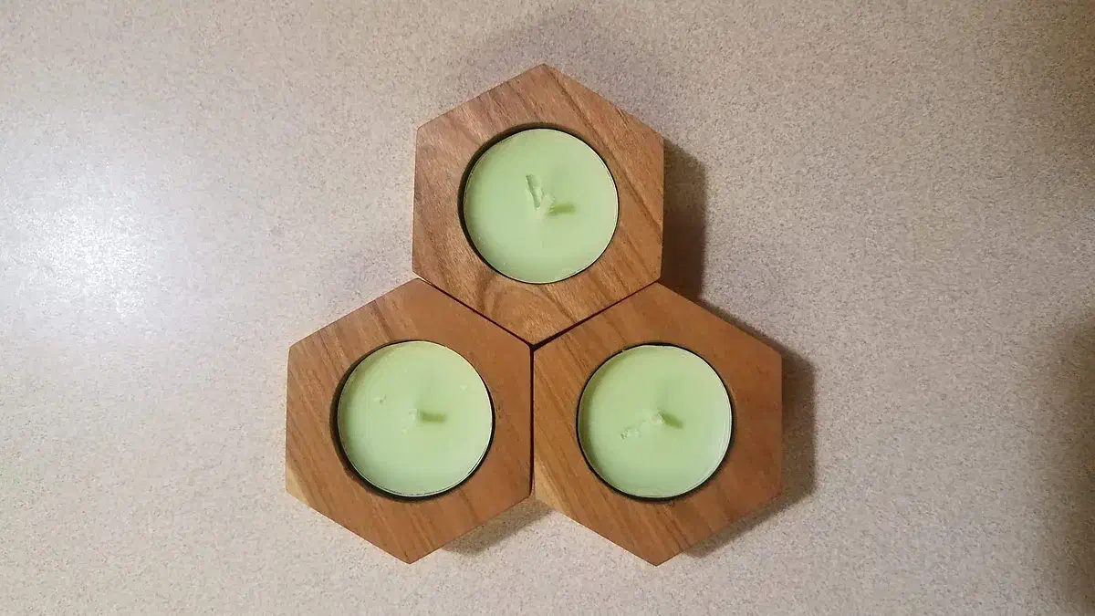 Three hexagonal wooden tealight holders arranged together around pale green candles