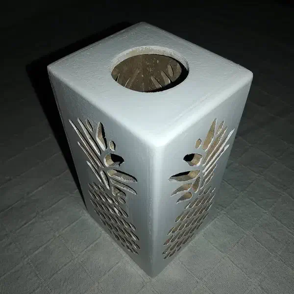 A white wooden box with pineapple-shaped cutouts and a round opening in the top