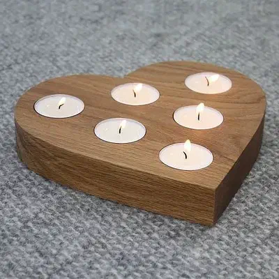 A thick wooden heart with six recessed white tealights on a gray surface