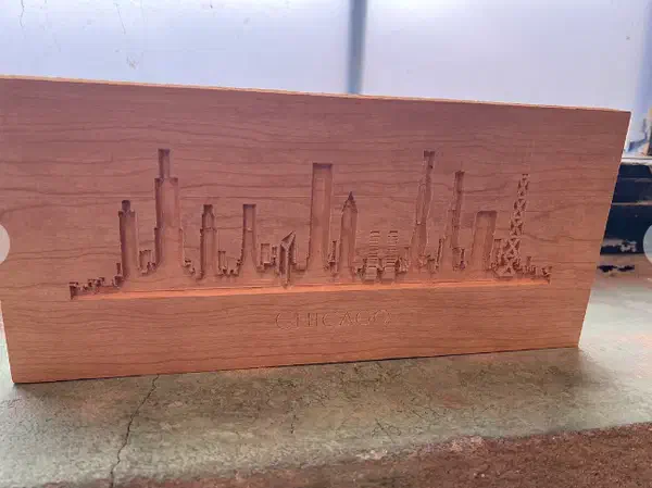 Finished cherry board with an engraved Chicago skyline, photographed on a workbench
