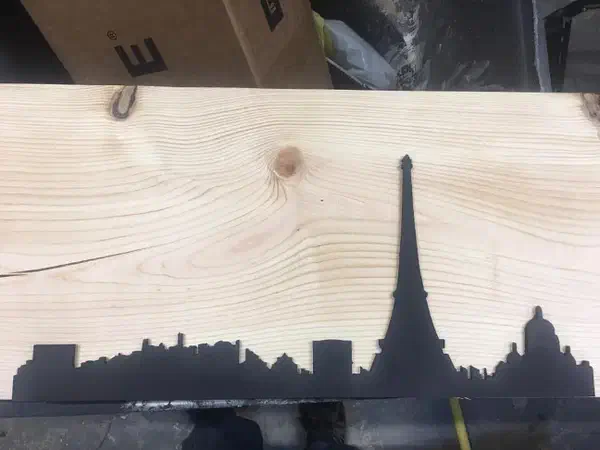 Black Paris skyline silhouette with the Eiffel Tower on a pale wood board, photographed in a workshop