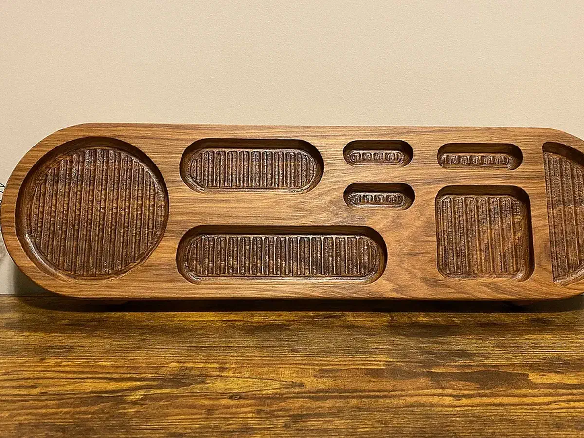 Finished long rounded wooden organizer with circular, rectangular, and narrow pockets and textured bottoms