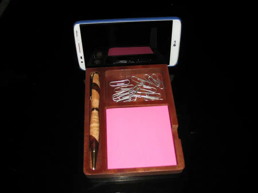 Finished wooden organizer holding a phone, pink note pad, pen, and paper clips