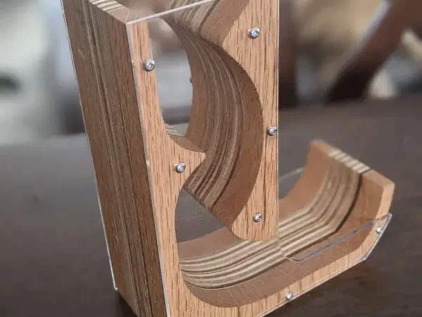 Layered wooden dice tumbler with clear side panels exposing its curved internal dice path