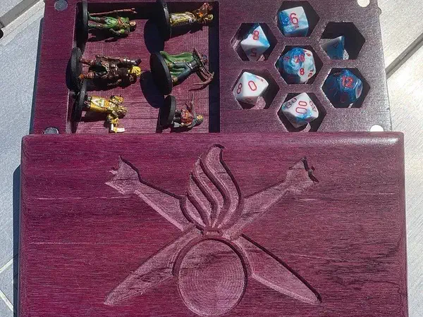 Open purple wooden dice box with separate pockets holding dice and miniature figures beside its decorated lid