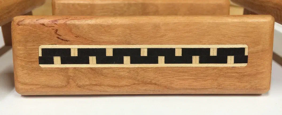 Wooden drawer pull with a black-and-cream geometric inlay strip