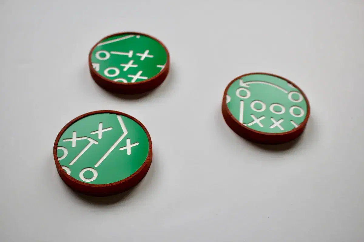 Green acrylic football-play designs fitted into reddish wooden coasters