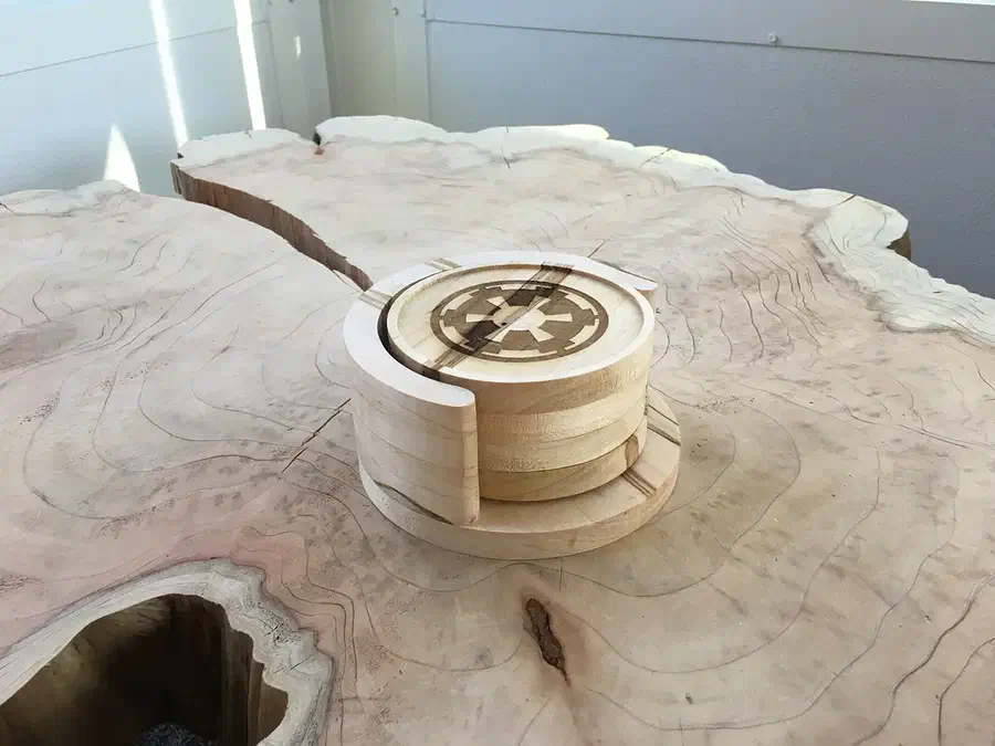 Round wooden coasters stacked in a curved wooden holder on a live-edge table