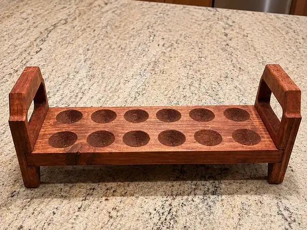 A wooden egg rack with raised handles and feet on a kitchen counter