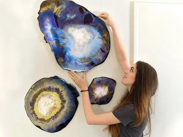 Three finished blue, purple, gold, white, and black resin geode wall pieces mounted together