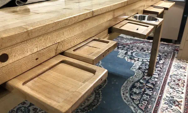 Carved wooden trays fitted along a gaming table, including a separate metal cup holder