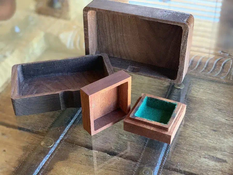 Large walnut card box and small green-lined jewelry box with their removable lids on a wooden table