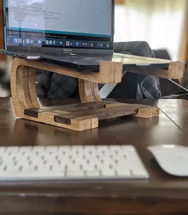 A laptop resting on a curved laminated plywood stand beside a separate keyboard
