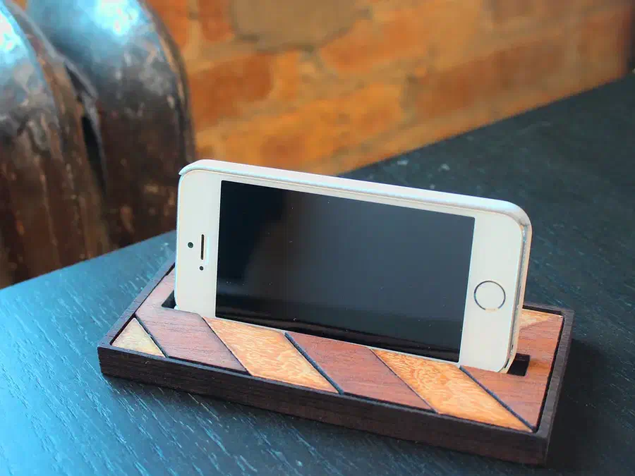 Phone resting horizontally in a wooden dock with contrasting chevron inlay