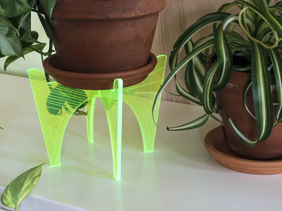 A terracotta plant pot on a neon yellow acrylic stand with engraved crossing lines