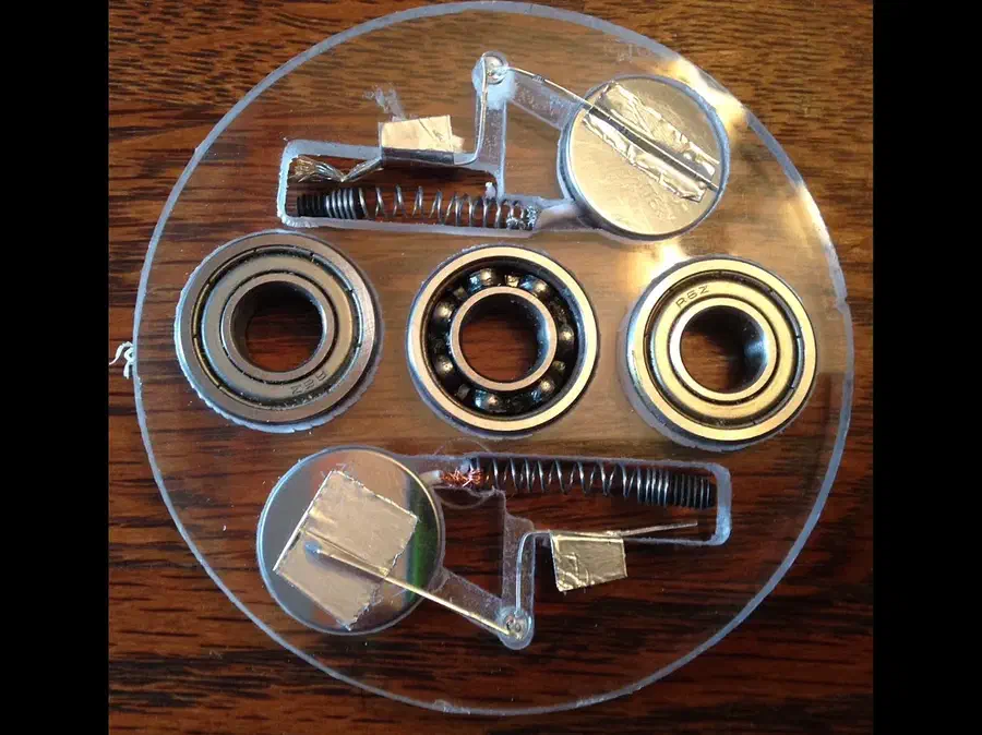 A clear circular acrylic spinner with bearings, a coin-cell battery, LED and small spring switch