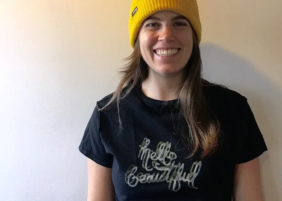 A person wearing a dark shirt printed with the handwritten words hello beautiful