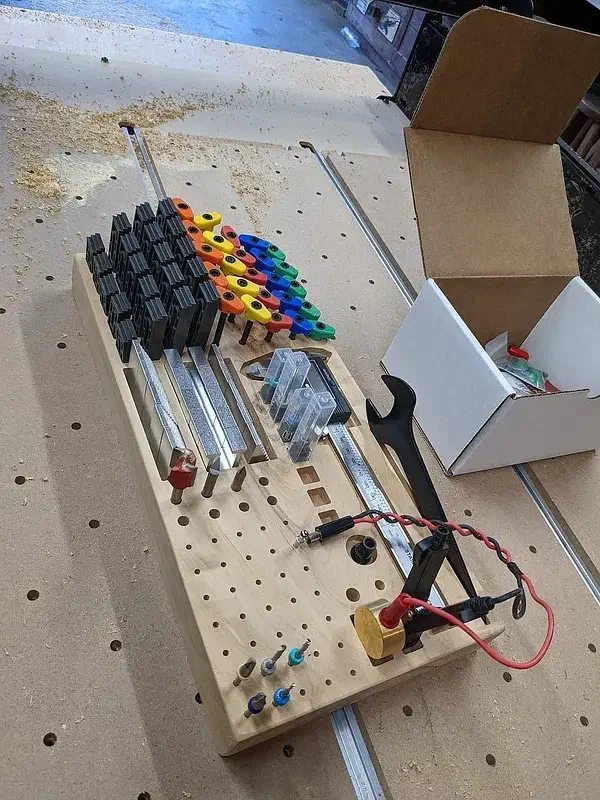 Long wooden sideboard tray holding router bits, clamps, measuring tools and probe wiring