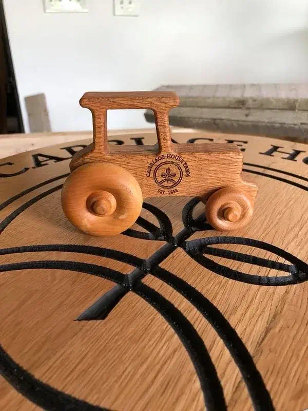 A small brown wooden farm tractor on a patterned wooden tabletop