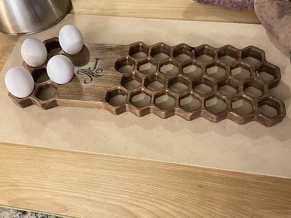 Long honeycomb-pattern wooden trivet holding four eggs