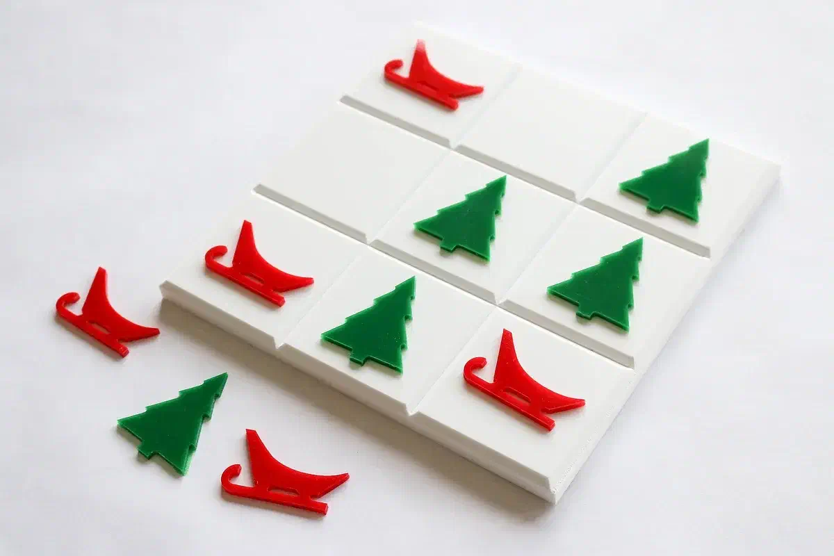 A white tic-tac-toe board with red sleigh and green Christmas-tree pieces