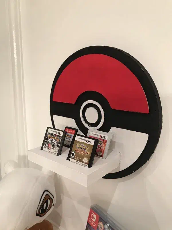 A painted red, white and black round wall shelf holding Nintendo DS game cartridges