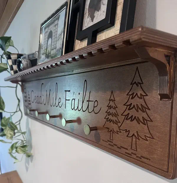 A carved wooden coat rack with pegs and a shelf holding framed pictures
