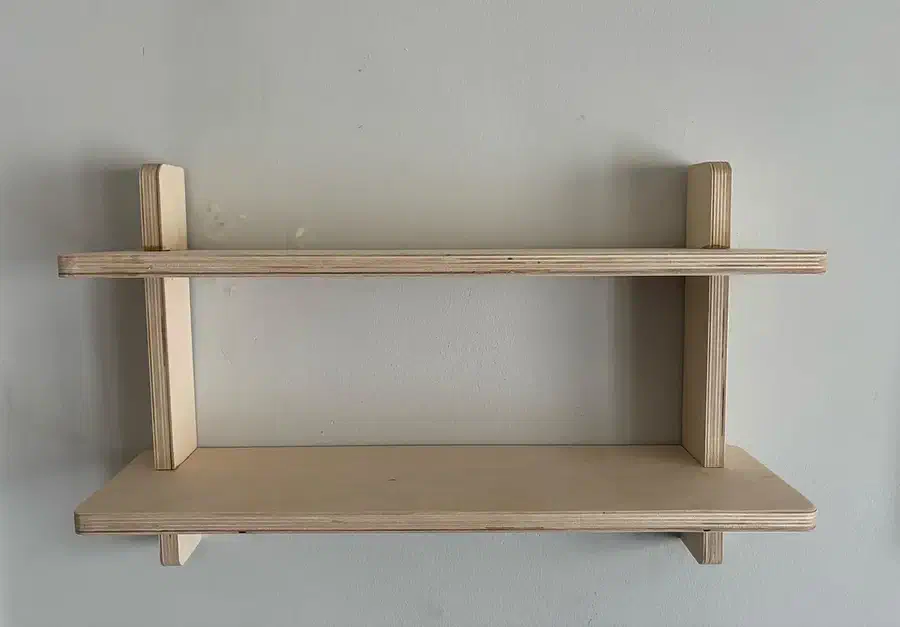 Two pale wooden shelves slotted into vertical wall supports