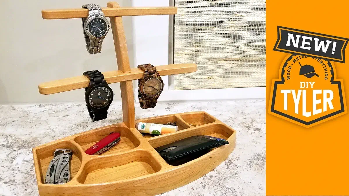 A two-tier wooden watch display with three watches and a divided tray holding a wallet and pocket tools
